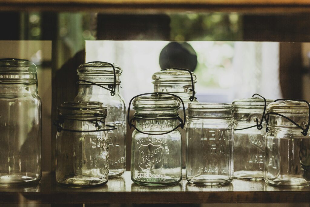 Collection of vintage mason jars on a shelf, showcasing rustic charm.