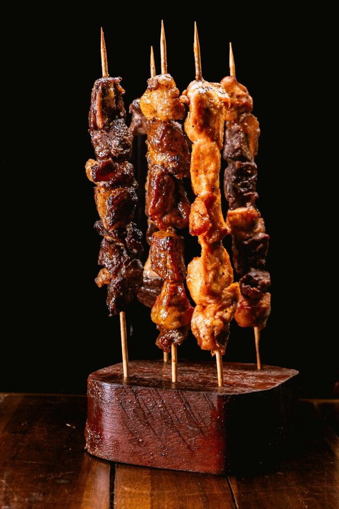 Savory grilled meat skewers displayed on a rustic wooden stand.