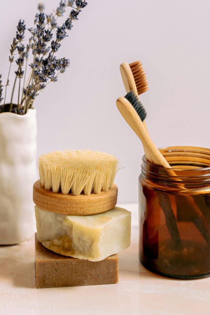 Rustic bath essentials including wooden toothbrushes, natural soaps, and a brush in a cozy setting.