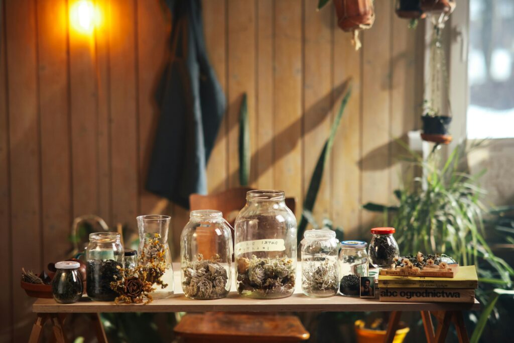 Warm indoor scene with dried herbs in glass jars on a rustic table.