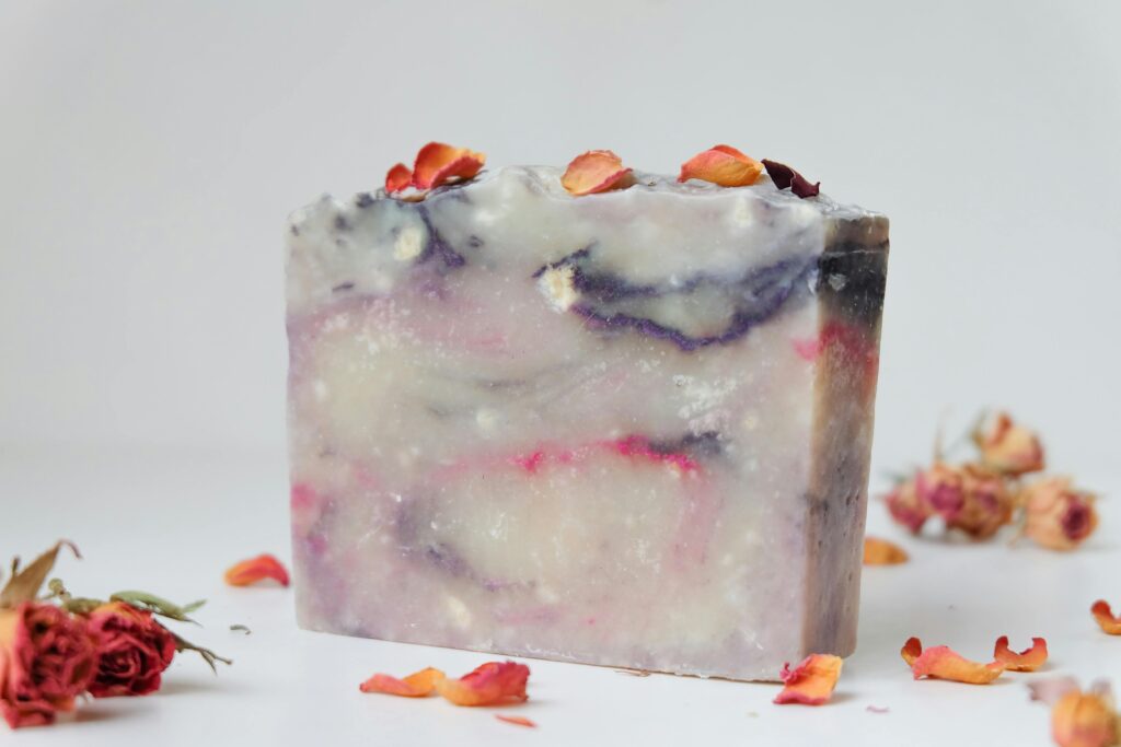 Artisan soap bar featuring dried rose petals on a white background.