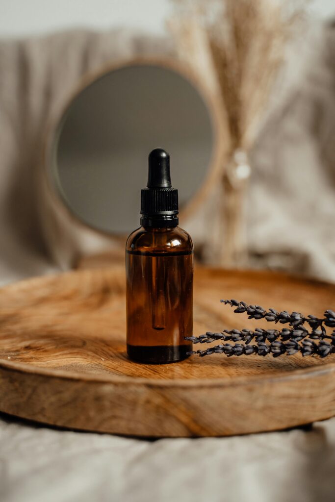 Amber glass dropper bottle on a wooden tray with lavender, ideal for skincare presentations.