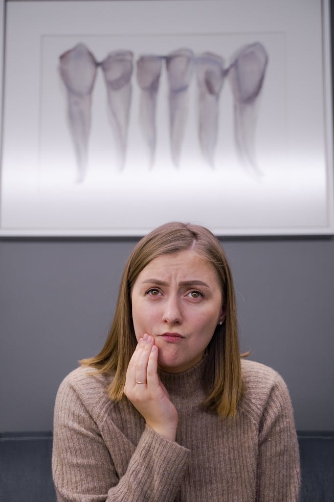 Caucasian woman feels toothache in modern dental clinic. Concerned expression. clove oil. natural remedy