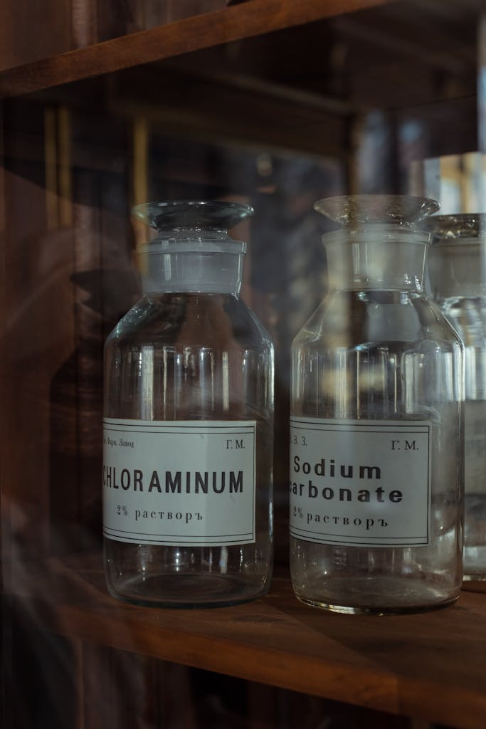 Close-up of vintage glass bottles labeled Chloraminum and Sodium Carbonate.