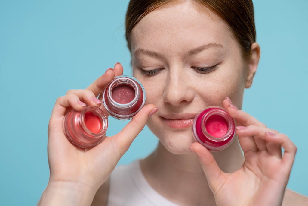 Close-up portrait of a woman holding colorful lip balm jars showcasing skincare and beauty products.