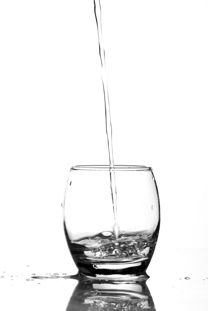Refreshing image of water being poured into a glass, emphasizing purity and clarity.