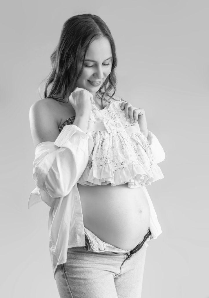 Elegant black and white portrait of a pregnant woman in a joyful pose.